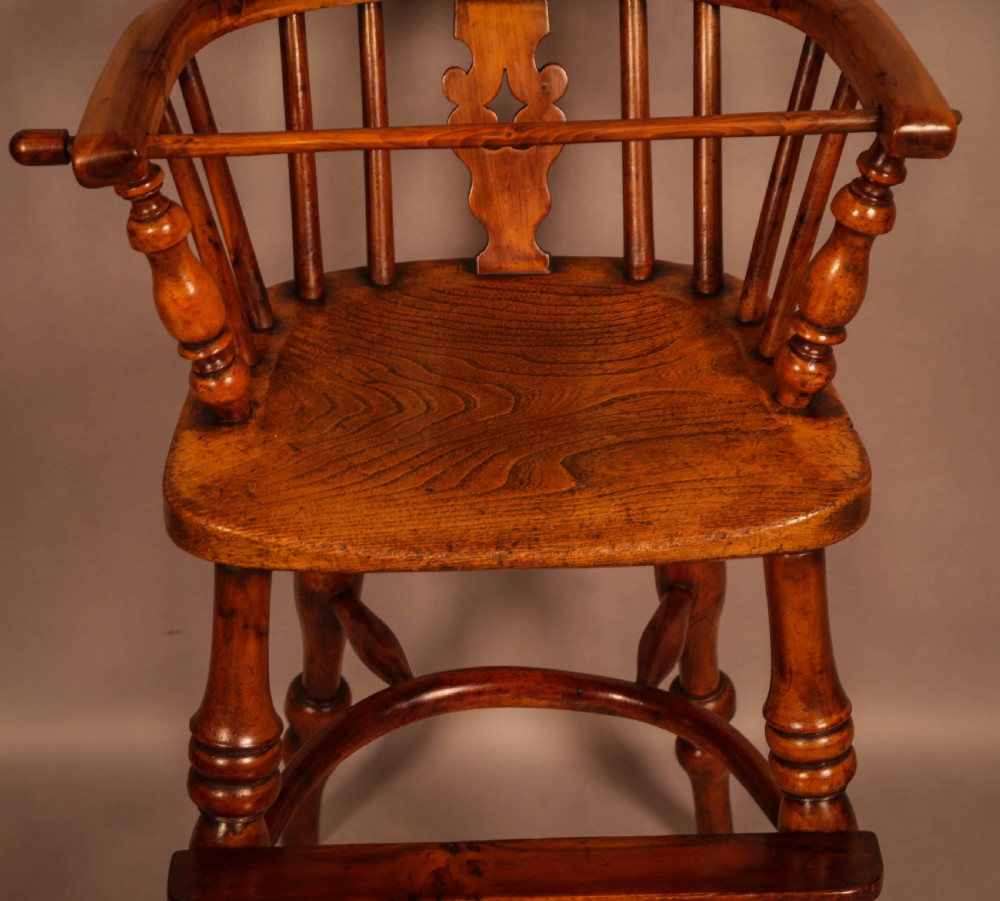 A yew wood Windsor childs high chair with a pierced splat back, turned legs, footrest, and safety bar. View VI