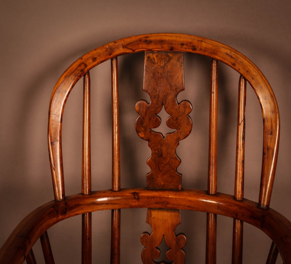 A yew wood Windsor childs high chair with a pierced splat back, turned legs, footrest, and safety bar. View X
