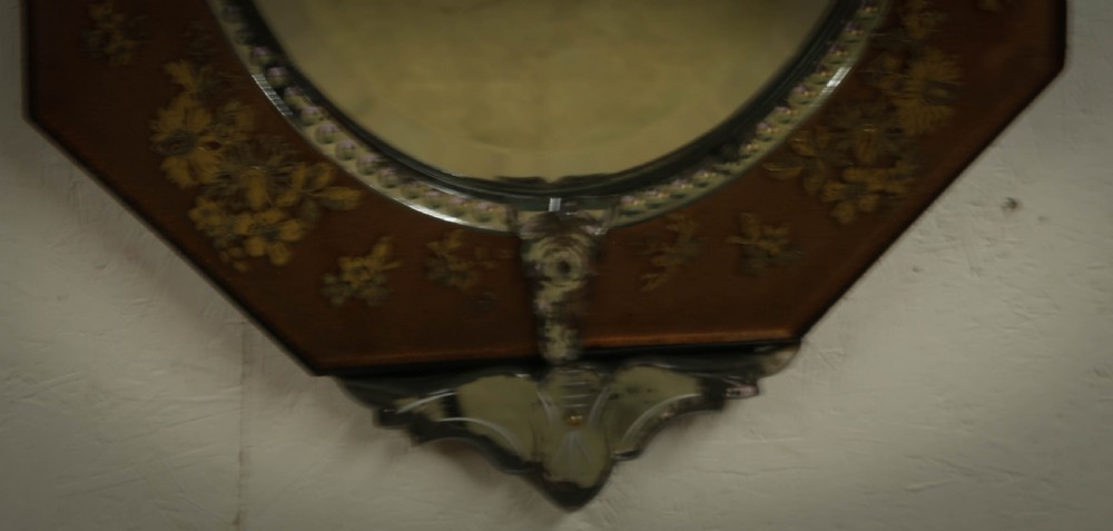 An octagonal Venetian wall mirror with a central oval plate, amber etched glass borders, and a decorative glass top crest. View IV