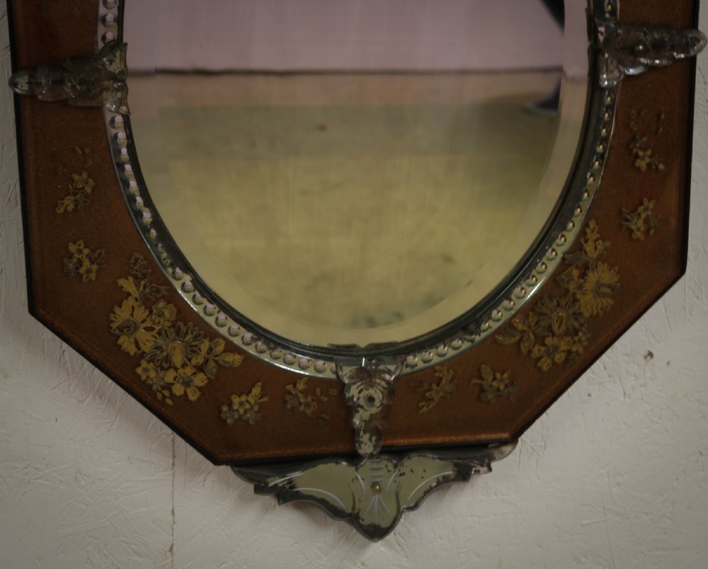 An octagonal Venetian wall mirror with a central oval plate, amber etched glass borders, and a decorative glass top crest. View V