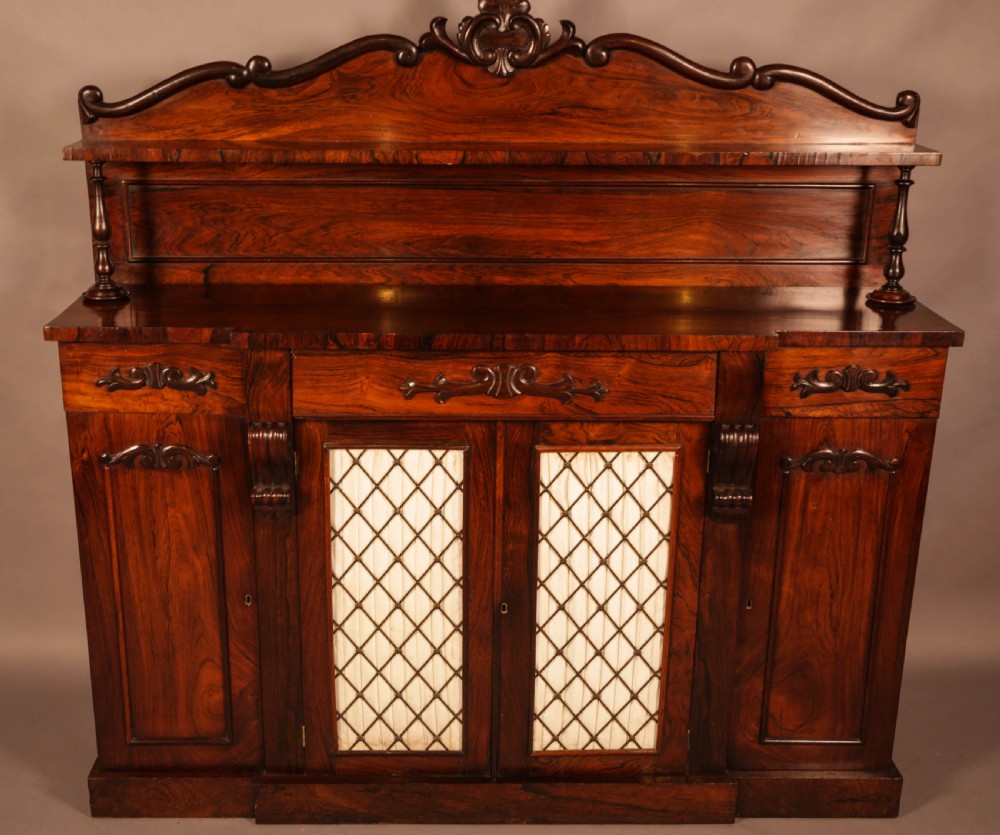 A Victorian rosewood four-door chiffonier featuring central wire latticework panels and a raised carved cresting rail on the backboard.