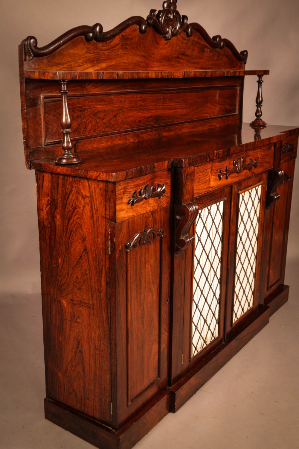 A Victorian rosewood four-door chiffonier featuring central wire latticework panels and a raised carved cresting rail on the backboard. View II