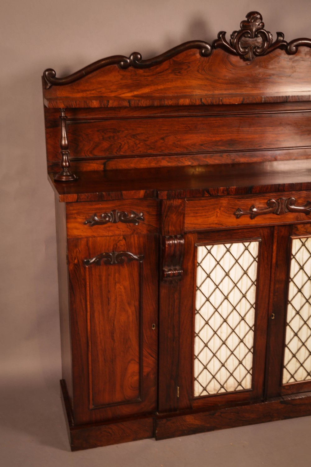 A Victorian rosewood four-door chiffonier featuring central wire latticework panels and a raised carved cresting rail on the backboard. View IV
