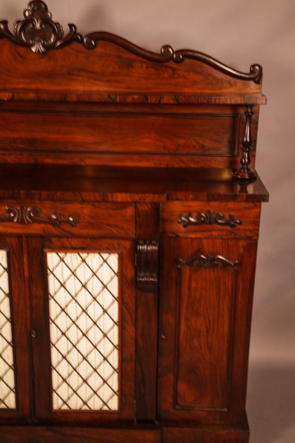 A Victorian rosewood four-door chiffonier featuring central wire latticework panels and a raised carved cresting rail on the backboard. View V