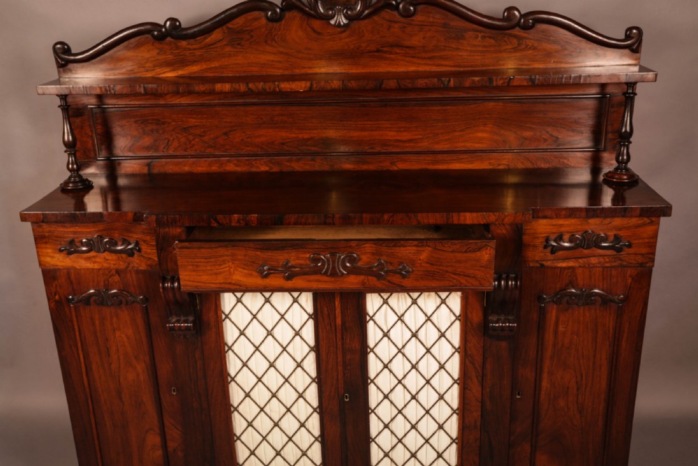 A Victorian rosewood four-door chiffonier featuring central wire latticework panels and a raised carved cresting rail on the backboard. View VI