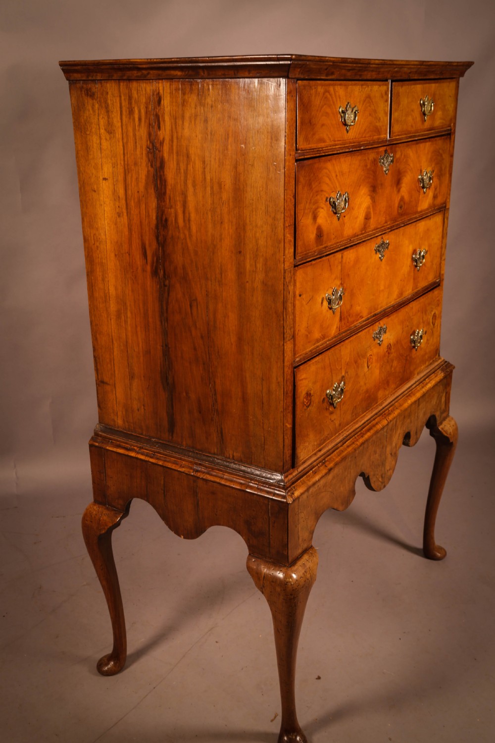 An 18th-century English walnut chest on stand featuring figured veneers, brass engraved escutcheons, a shaped apron frieze, and cabriole legs with pad feet. View II