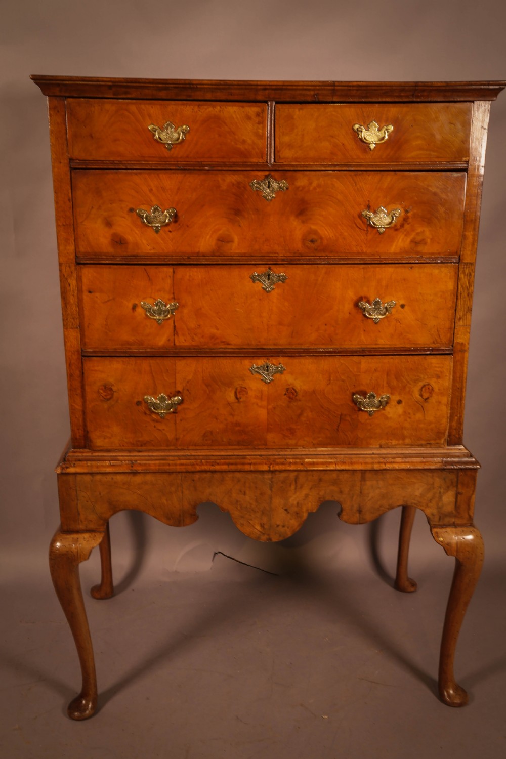 An 18th-century English walnut chest on stand featuring figured veneers, brass engraved escutcheons, a shaped apron frieze, and cabriole legs with pad feet. View III