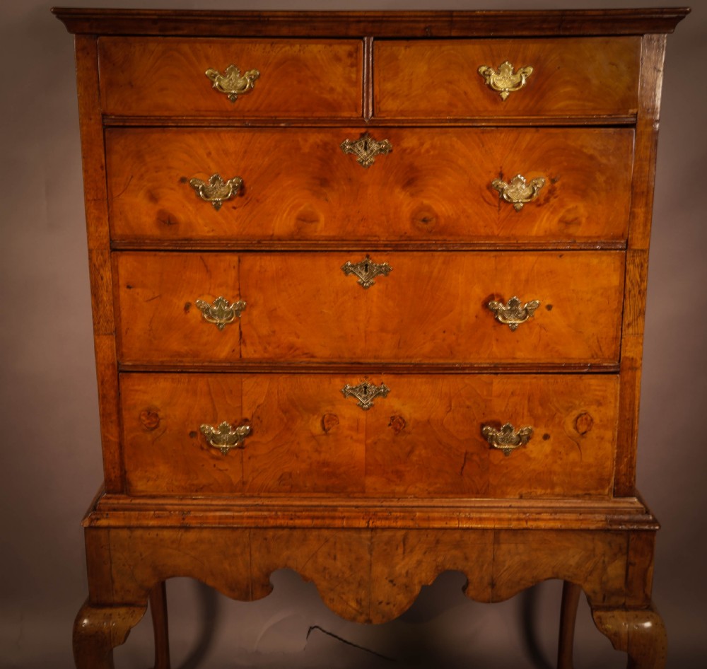 An 18th-century English walnut chest on stand featuring figured veneers, brass engraved escutcheons, a shaped apron frieze, and cabriole legs with pad feet. View IV