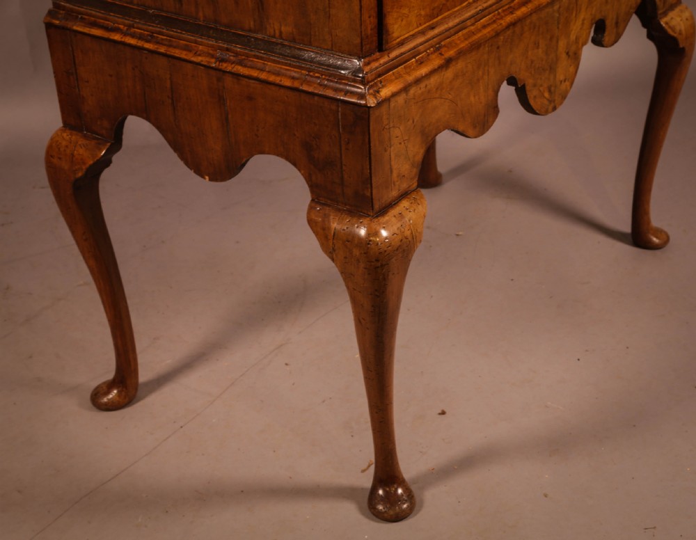 An 18th-century English walnut chest on stand featuring figured veneers, brass engraved escutcheons, a shaped apron frieze, and cabriole legs with pad feet. View VII