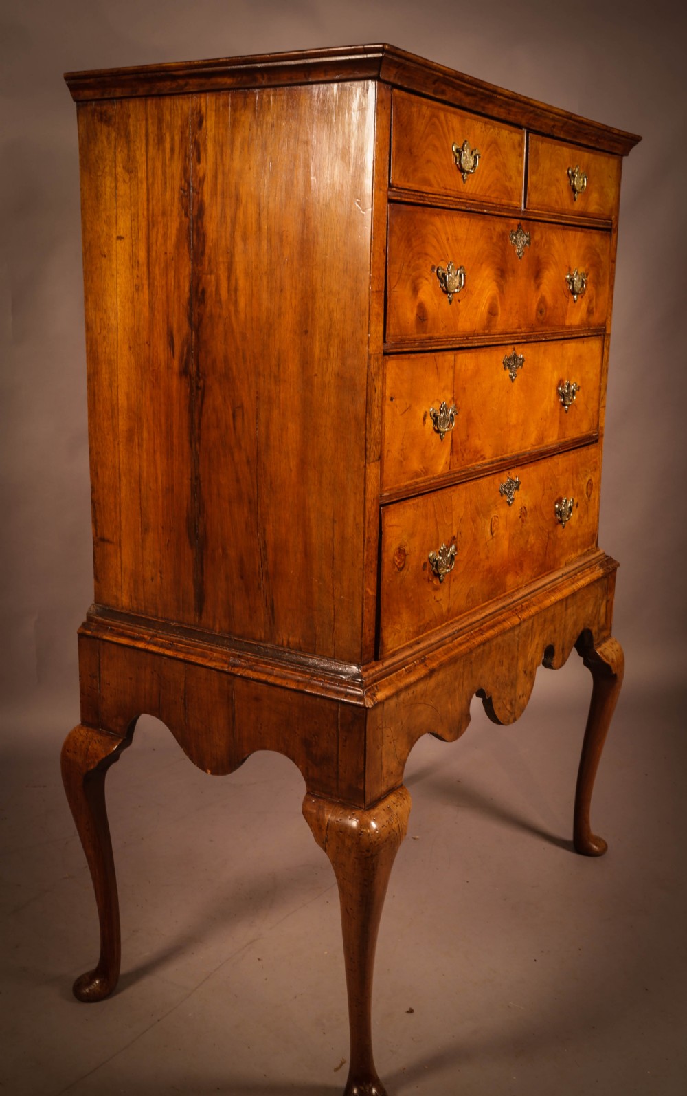 An 18th-century English walnut chest on stand featuring figured veneers, brass engraved escutcheons, a shaped apron frieze, and cabriole legs with pad feet. View VIII