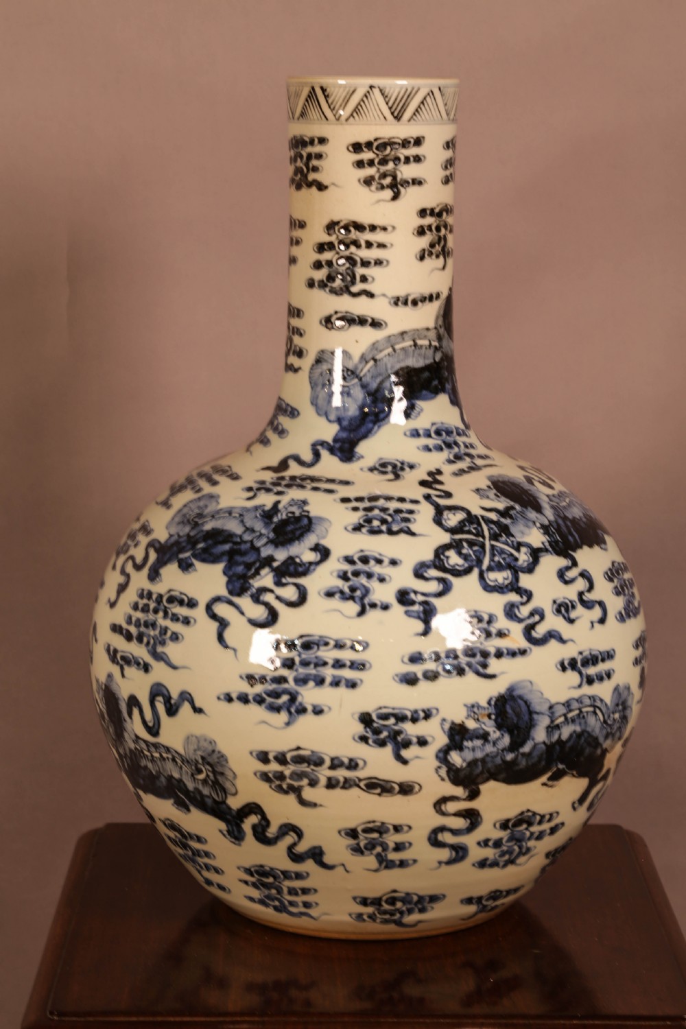 A large cylindrical and globular porcelain vase featuring hand-painted blue foo dogs and cloud motifs against a white glaze.