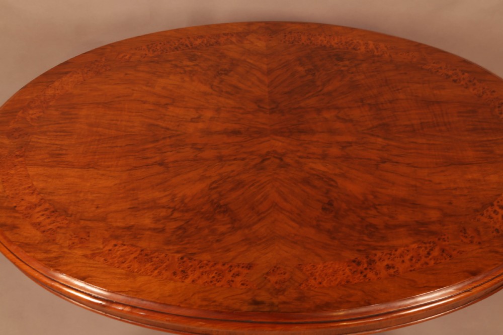 An oval Victorian burr walnut table featuring a figured veneer top and a central carved pedestal with four scroll feet. View VIII