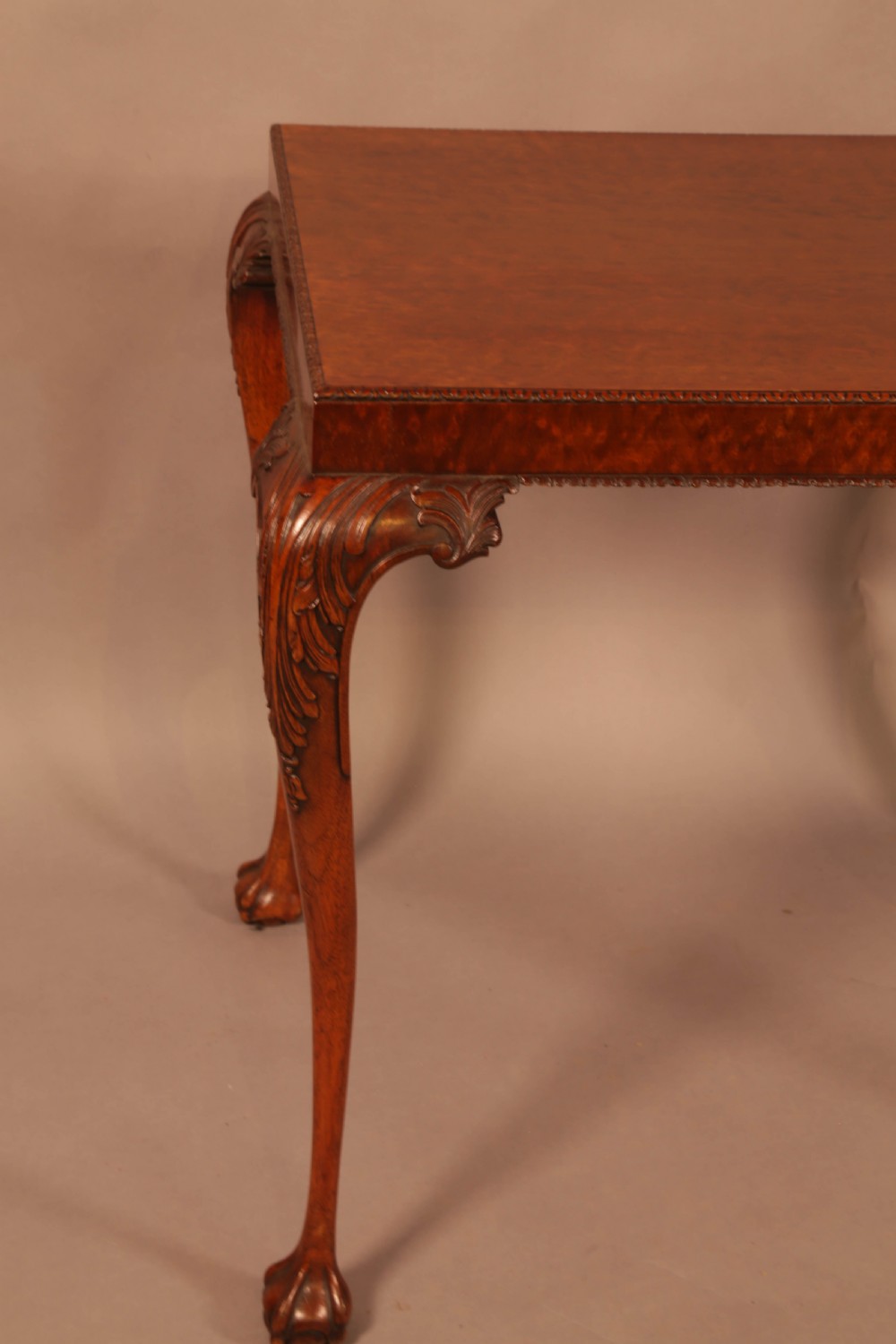 A Chippendale style wooden silver table featuring cabriole legs with carved knees, ball and claw feet, and a rectangular burr-veneered top. View IV