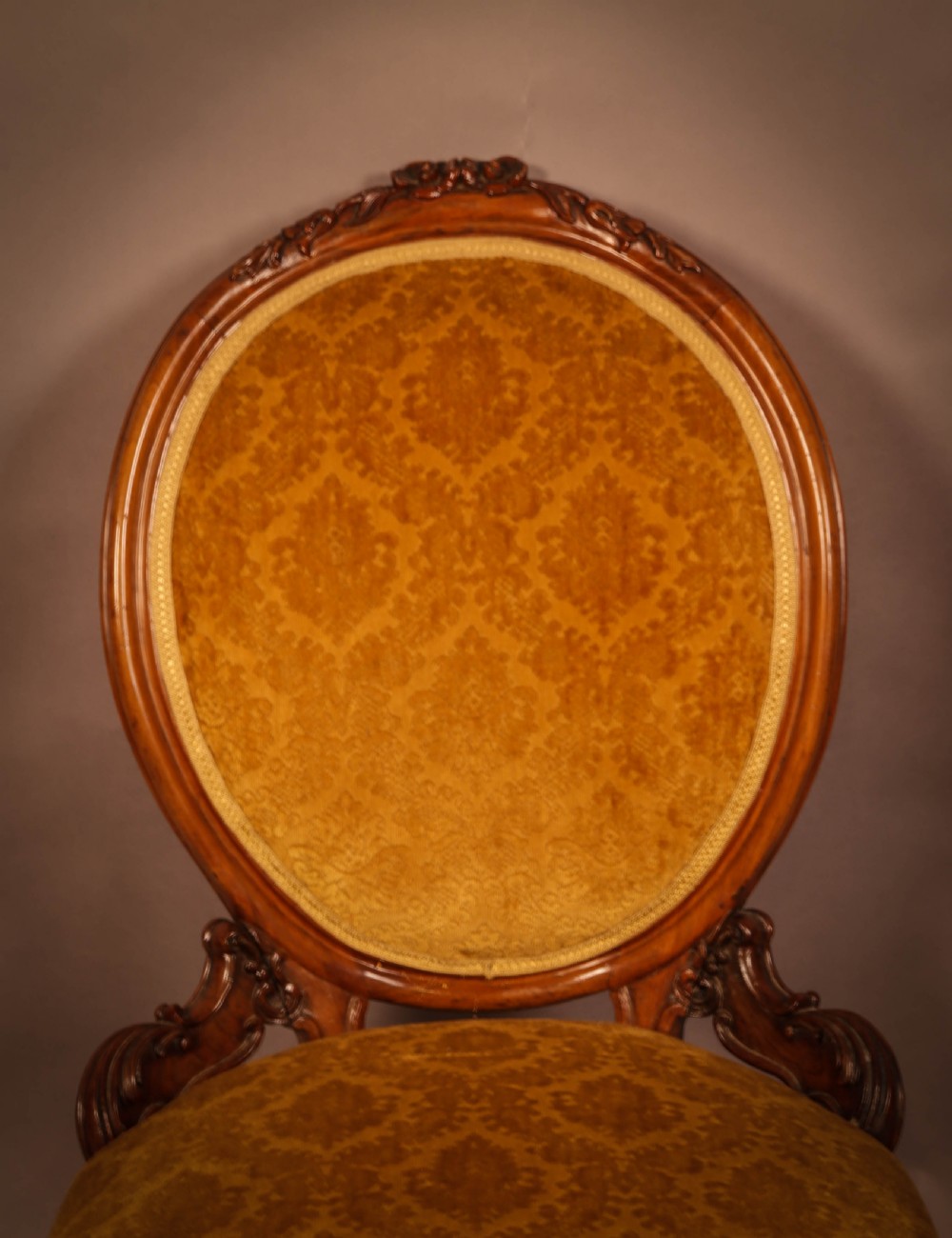 A Victorian walnut nursing chair featuring carved framework, an oval backrest, and golden patterned upholstery. View II