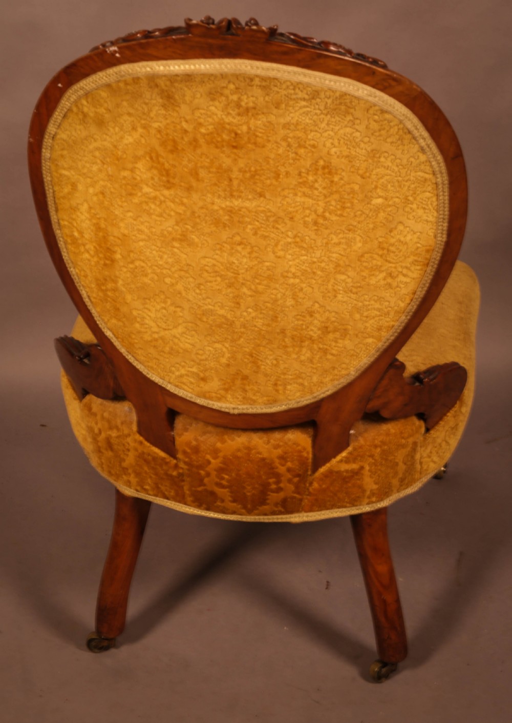 A Victorian walnut nursing chair featuring carved framework, an oval backrest, and golden patterned upholstery. View IV