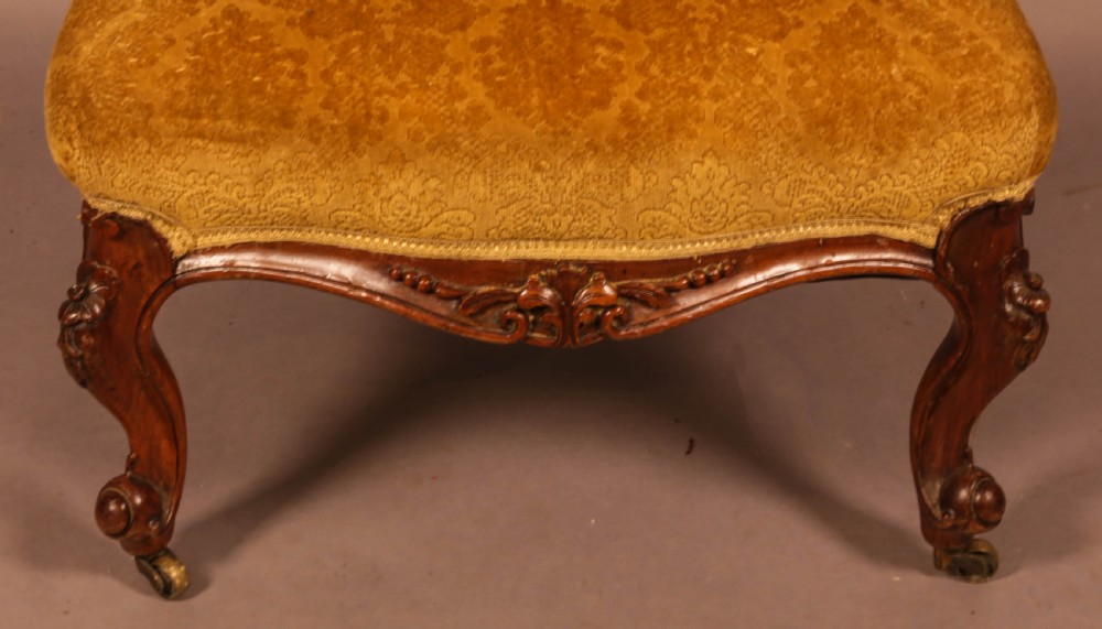 A Victorian walnut nursing chair featuring carved framework, an oval backrest, and golden patterned upholstery. View VII