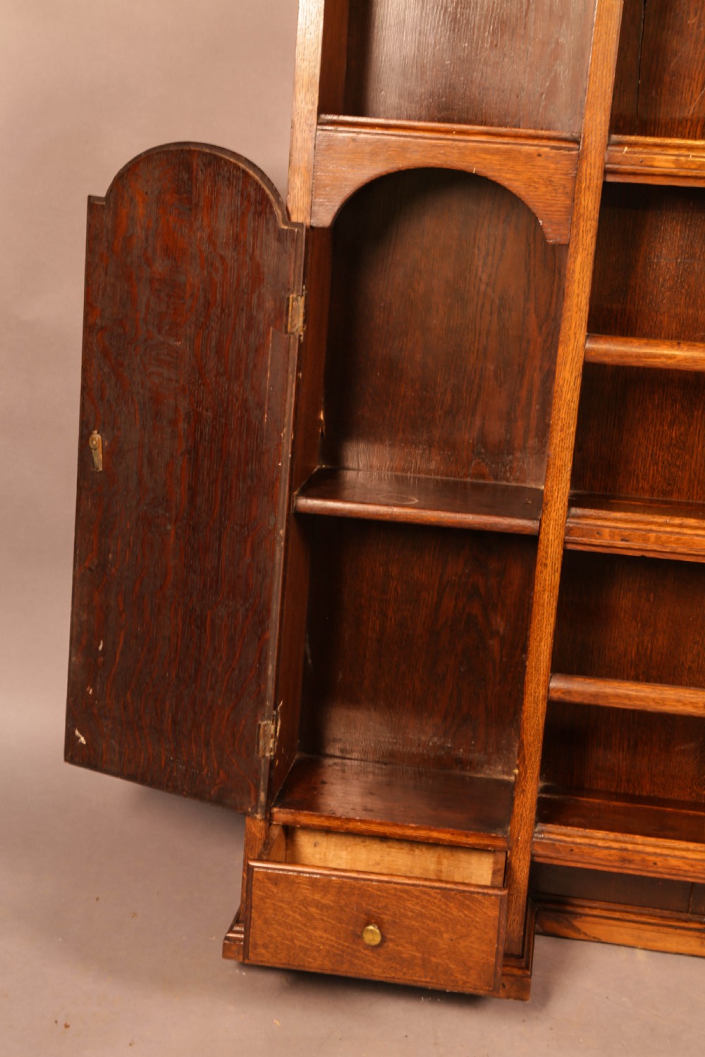 Large dark oak plate rack featuring open shelves with grooved runners, flanked by two side cupboards, topped with a geometric pierced fretwork frieze and dentil cornice. View V