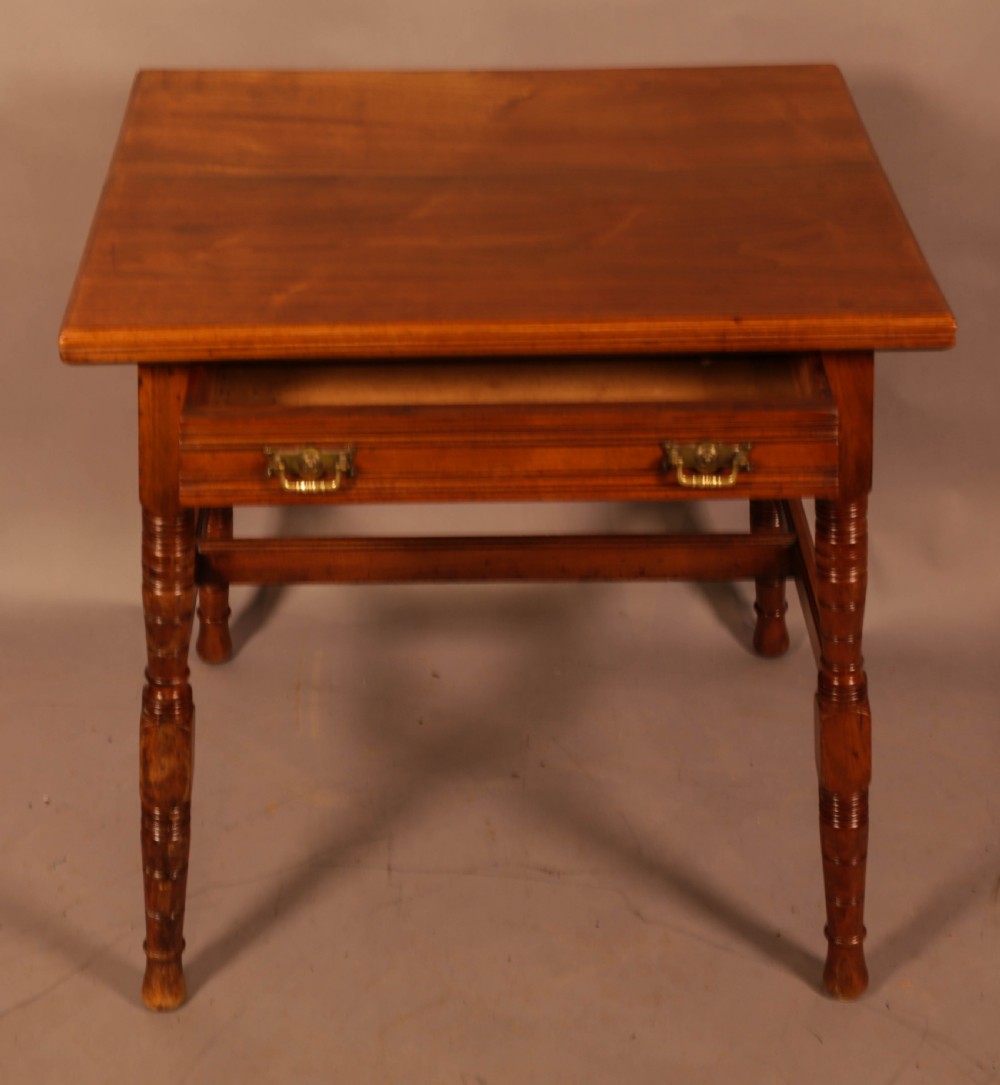 An Aesthetic Movement warm brown walnut occasional table with turned legs, a single drawer featuring brass handles, and a lower H-stretcher. View II