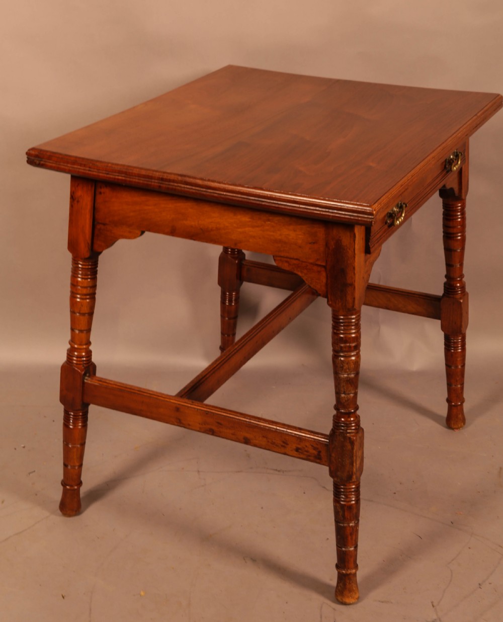 An Aesthetic Movement warm brown walnut occasional table with turned legs, a single drawer featuring brass handles, and a lower H-stretcher. View V