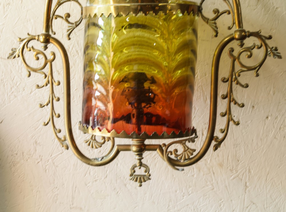Victorian brass hanging lantern featuring an ornate scrollwork frame enclosing a cylindrical shade with graded yellow and red glass. View IV