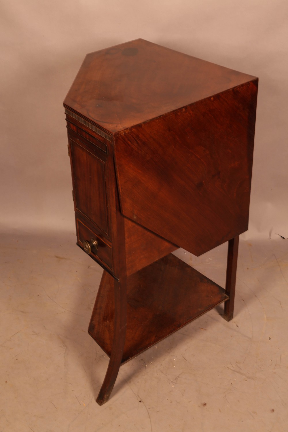 An 18th-century Georgian mahogany corner washstand featuring a hinged splashback, central basin opening, single cupboard door, brass knob handles, and a lower undertier shelf. View III