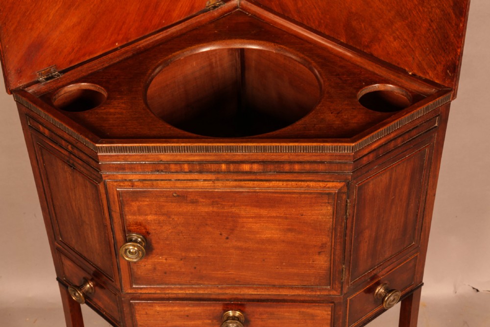 An 18th-century Georgian mahogany corner washstand featuring a hinged splashback, central basin opening, single cupboard door, brass knob handles, and a lower undertier shelf. View IX