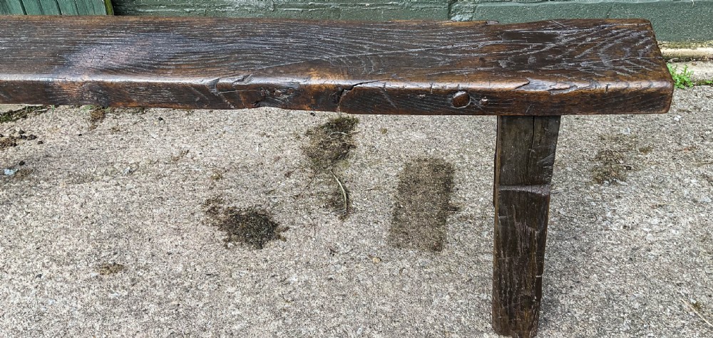 A long 18th-century dark oak trestle bench with a plank seat and splayed supports. View III