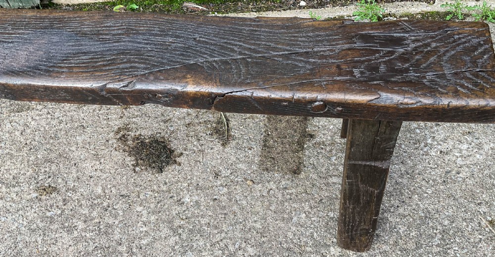 A long 18th-century dark oak trestle bench with a plank seat and splayed supports. View IV