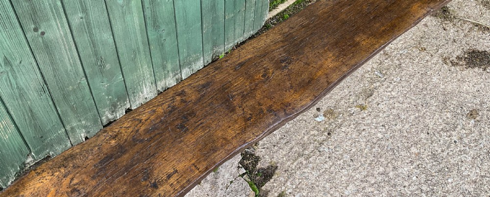An 18th-century long solid oak trestle bench featuring a thick timber top and four splayed legs. View IX