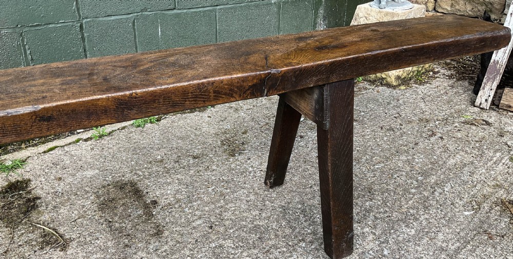 An exceptionally long 18th-century dark oak bench with a single-plank seat and splayed rectangular legs. View IV