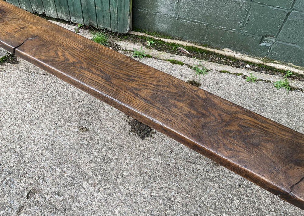 An exceptionally long 18th-century dark oak bench with a single-plank seat and splayed rectangular legs. View VI
