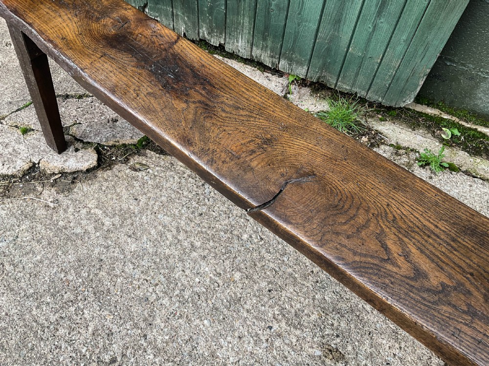 An exceptionally long 18th-century dark oak bench with a single-plank seat and splayed rectangular legs. View VIII