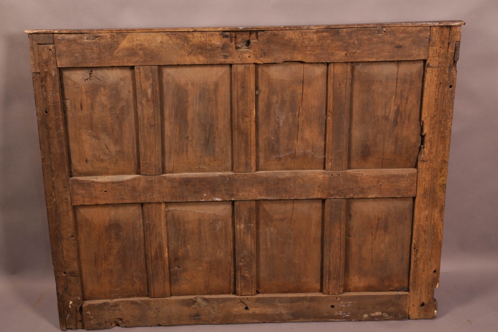 A 17th-century carved dark oak wall panel featuring an inscribed top frieze reading Oliver and Joanna Dickonson, framing double-tier field panels with wooden peg hooks. View VIII