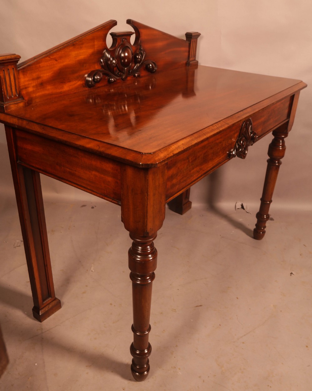 A Victorian mahogany serving table featuring a carved decorative backboard and turned front legs. View II