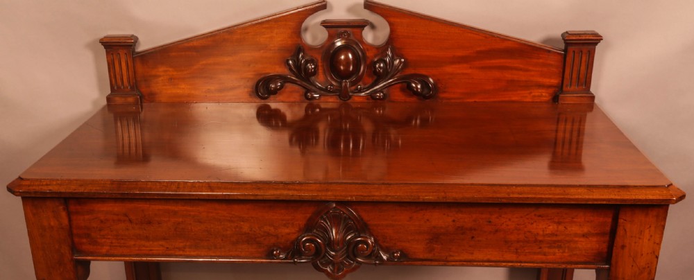 A Victorian mahogany serving table featuring a carved decorative backboard and turned front legs. View IV