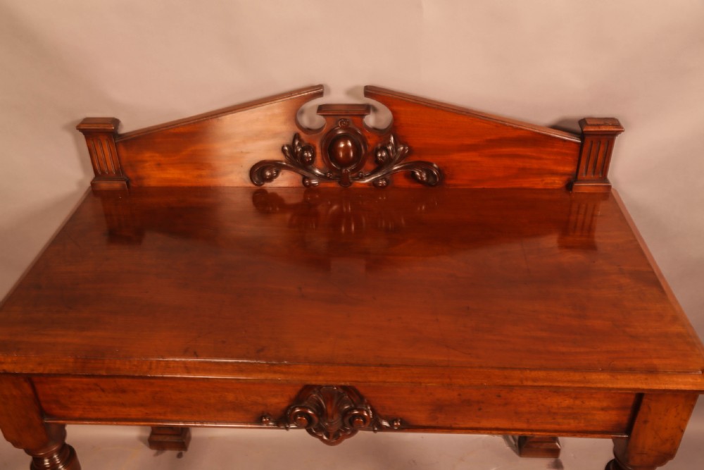 A Victorian mahogany serving table featuring a carved decorative backboard and turned front legs. View V