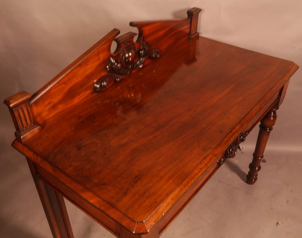 A Victorian mahogany serving table featuring a carved decorative backboard and turned front legs. View VI
