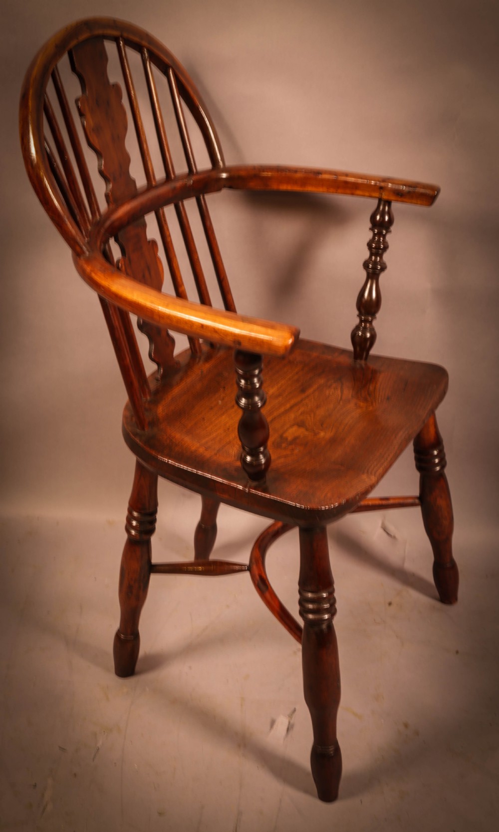 An antique 19th-century yew wood Windsor armchair featuring a hoop back, pierced central splat, turned legs, and a bow stretcher. View II