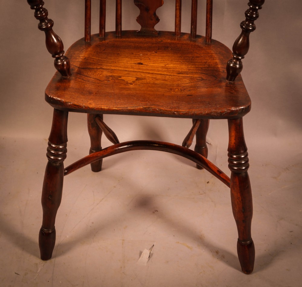 An antique 19th-century yew wood Windsor armchair featuring a hoop back, pierced central splat, turned legs, and a bow stretcher. View III