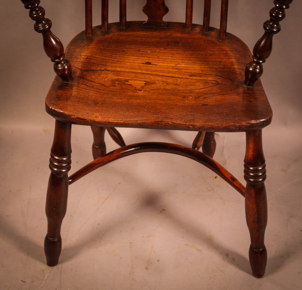 An antique 19th-century yew wood Windsor armchair featuring a hoop back, pierced central splat, turned legs, and a bow stretcher. View V