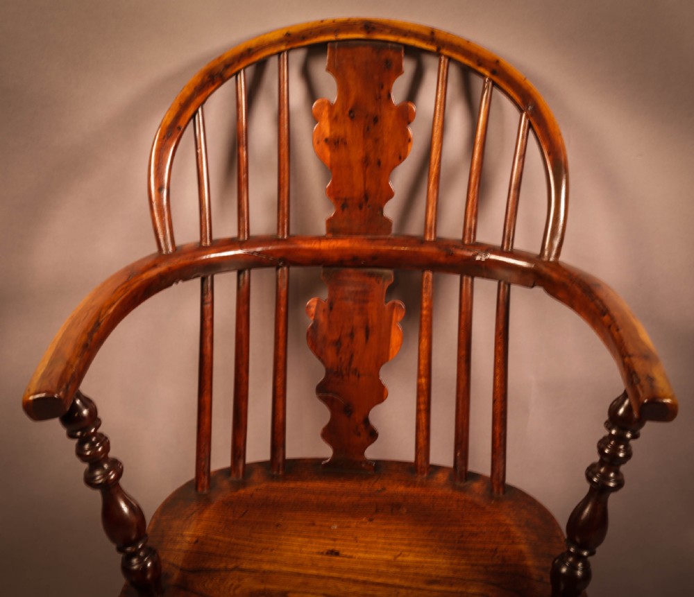 An antique 19th-century yew wood Windsor armchair featuring a hoop back, pierced central splat, turned legs, and a bow stretcher. View VI
