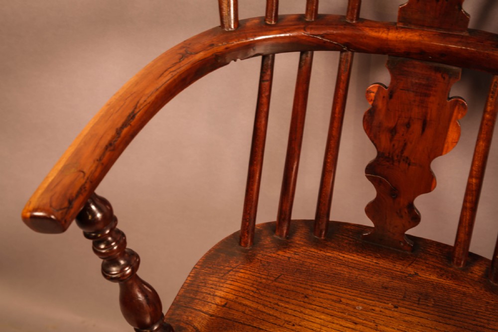 An antique 19th-century yew wood Windsor armchair featuring a hoop back, pierced central splat, turned legs, and a bow stretcher. View VII