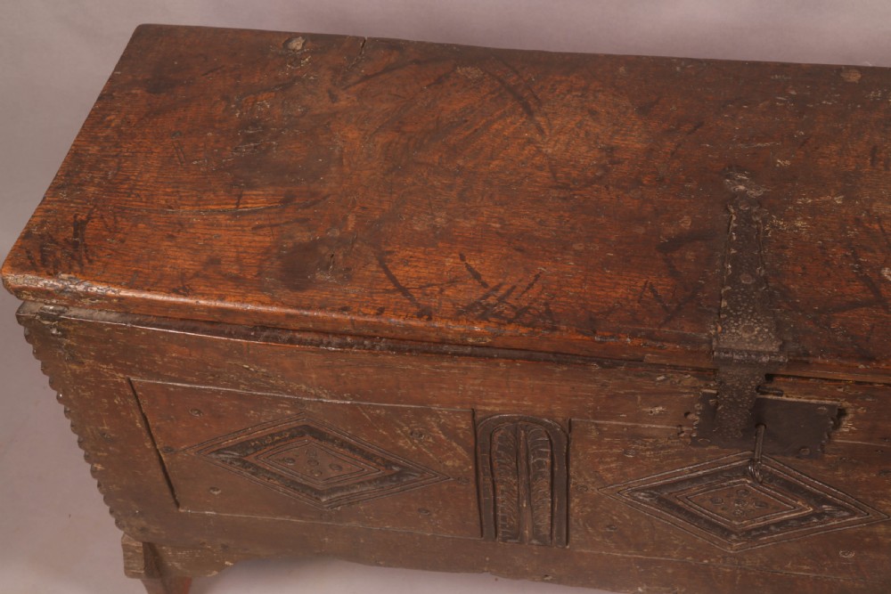 A dark oak early seventeenth-century five-plank coffer featuring carved lozenge panel decoration and hand-forged iron hardware. View V