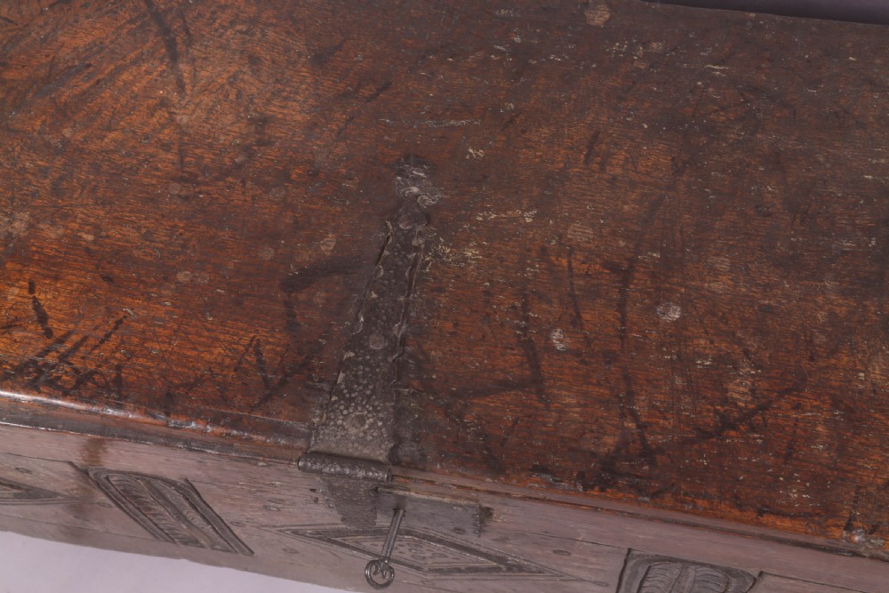 A dark oak early seventeenth-century five-plank coffer featuring carved lozenge panel decoration and hand-forged iron hardware. View XI