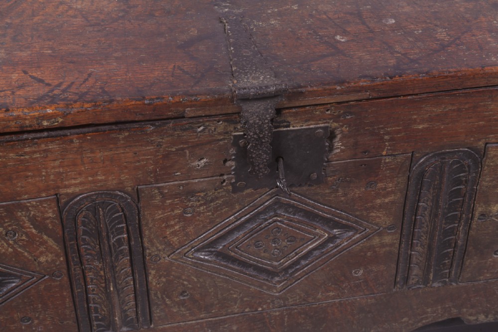 A dark oak early seventeenth-century five-plank coffer featuring carved lozenge panel decoration and hand-forged iron hardware. View XII