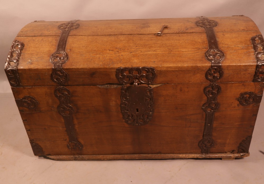 An 18th-century oak trunk with a domed lid and decorative iron strapwork.