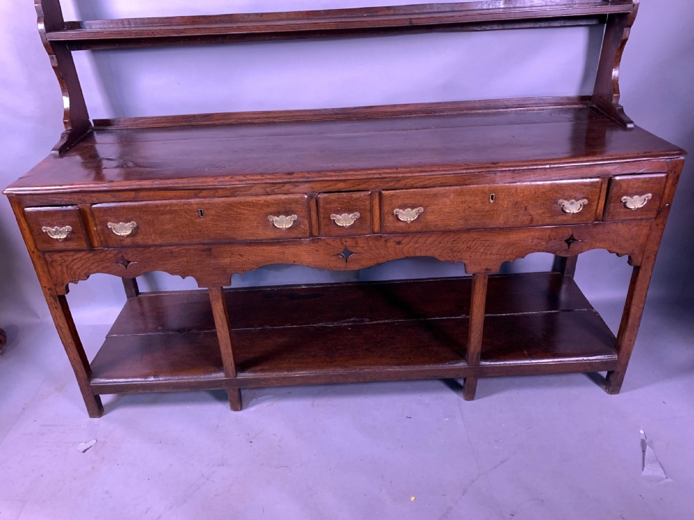 An 18th-century oak Welsh dresser featuring an open rack top with plate hooks, a central base with multiple drawers, and a lower pot board shelf. View II
