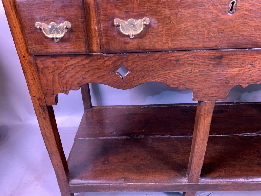 An 18th-century oak Welsh dresser featuring an open rack top with plate hooks, a central base with multiple drawers, and a lower pot board shelf. View V