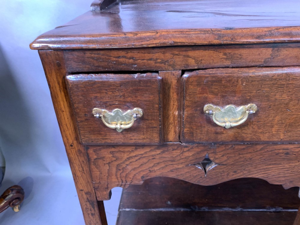 An 18th-century oak Welsh dresser featuring an open rack top with plate hooks, a central base with multiple drawers, and a lower pot board shelf. View VI