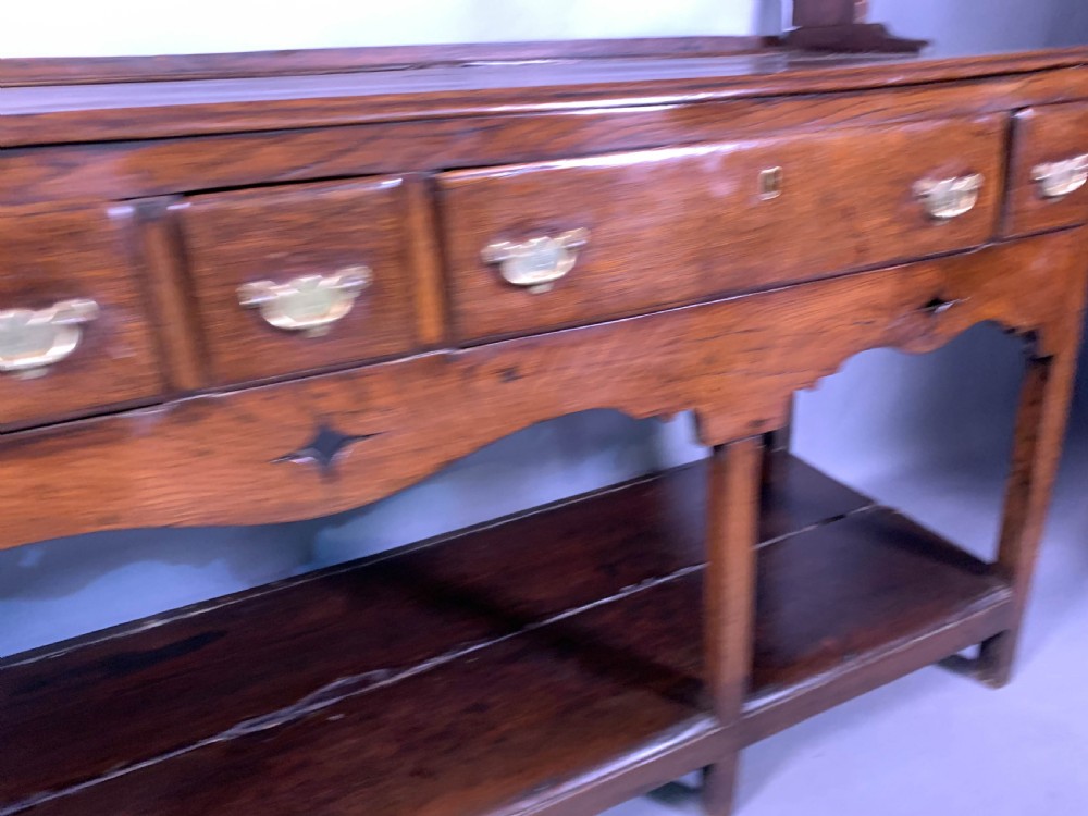 An 18th-century oak Welsh dresser featuring an open rack top with plate hooks, a central base with multiple drawers, and a lower pot board shelf. View VII